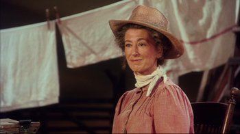 Movie still from “Oklahoma!” (1999), directed by Trevor Nunn – A woman wearing a straw hat and a pink dress; Close Up shot, Low angle