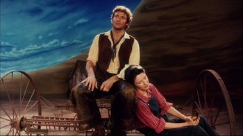 Movie still from “Oklahoma!” (1999), directed by Trevor Nunn – A man and a woman sitting next to each other; Wide shot, Low angle