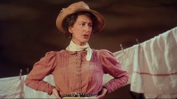 Movie still from “Oklahoma!” (1999), directed by Trevor Nunn – A woman in a pink dress and a cowboy hat; Medium shot, Low angle