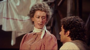 Movie still from “Oklahoma!” (1999), directed by Trevor Nunn – An older woman wearing a neck scarf talking to a younger man; Close Up shot, Over the shoulder angle