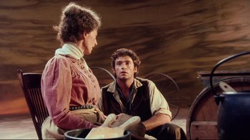 Movie still from “Oklahoma!” (1999), directed by Trevor Nunn – A man and a woman sitting on a chair; Medium shot, Over the shoulder angle