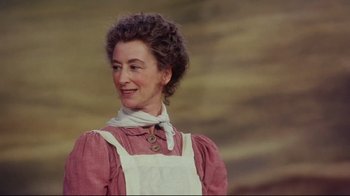 Movie still from “Oklahoma!” (1999), directed by Trevor Nunn – An older woman wearing a pink dress and a white neck scarf; Close Up shot, Low angle