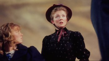 Movie still from “Oklahoma!” (1999), directed by Trevor Nunn – A woman wearing a black dress and a red hat; Medium shot, Low angle