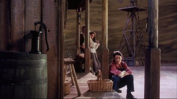 Movie still from “Oklahoma!” (1999), directed by Trevor Nunn – A group of people sitting on a wooden floor; Wide shot, High angle
