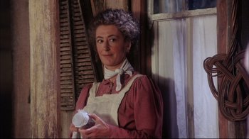 Movie still from “Oklahoma!” (1999), directed by Trevor Nunn – An older woman holding a cup in her hands; Medium shot, Low angle