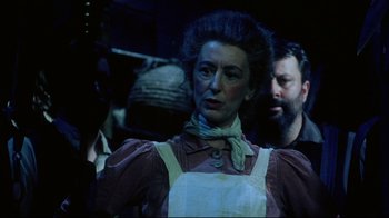 Movie still from “Oklahoma!” (1999), directed by Trevor Nunn – An older woman wearing an apron in a dark room; Close Up shot, Low angle