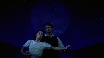 Movie still from “Oklahoma!” (1999), directed by Trevor Nunn – A man and a woman standing next to each other in front of the moon; Medium shot, Low angle