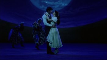 Movie still from “Oklahoma!” (1999), directed by Trevor Nunn – A man and a woman dancing on a stage in front of the moon; Wide shot, Low angle