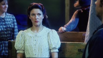 Movie still from “Oklahoma!” (1999), directed by Trevor Nunn – A woman in a white dress sitting next to a man in a blue shirt; Medium shot, Over the shoulder angle