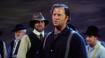 Movie still from “Oklahoma!” (1999), directed by Trevor Nunn – A man with a hat and a beard standing next to another man with a hat; Medium shot, Low angle