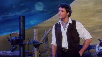 Movie still from “Oklahoma!” (1999), directed by Trevor Nunn – A man standing in front of a wooden fence; Medium shot, Over the shoulder angle