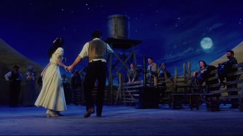 Movie still from “Oklahoma!” (1999), directed by Trevor Nunn – A group of people standing on top of a platform; Wide shot, Low angle