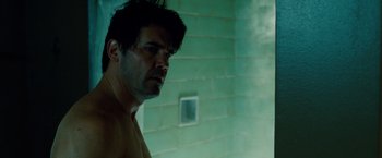 Movie still from “Oldboy” (2013), directed by Spike Lee – A shirtless man in a green room with smoke coming out of his mouth; Close Up shot, Over the shoulder angle