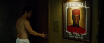 Movie still from “Oldboy” (2013), directed by Spike Lee – A man standing in front of a door with a poster hanging on the wall; Medium shot, Over the shoulder angle