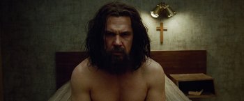 Movie still from “Oldboy” (2013), directed by Spike Lee – A man with long hair and beard sitting in a bed; Close Up shot, Low angle