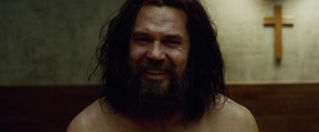 Movie still from “Oldboy” (2013), directed by Spike Lee – A man with long hair and a beard smiling for the camera; Close Up shot, Over the shoulder angle