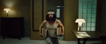 Movie still from “Oldboy” (2013), directed by Spike Lee – A man in a tank top and a headband is standing in front of a door; Medium shot, Low angle