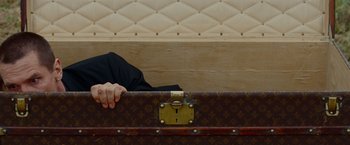 Movie still from “Oldboy” (2013), directed by Spike Lee – A man sitting on top of a louis vuitton suitcase; Medium shot, Low angle