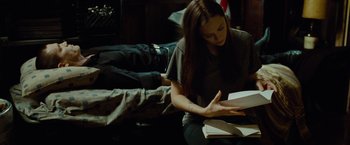 Movie still from “Oldboy” (2013), directed by Spike Lee – A woman sitting on the ground reading a book; Medium shot, Over the shoulder angle