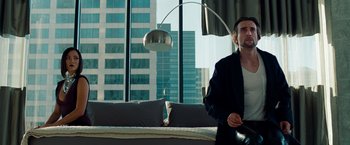 Movie still from “Oldboy” (2013), directed by Spike Lee – A man sitting on top of a couch next to a window; Medium shot, Low angle