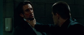 Movie still from “Oldboy” (2013), directed by Spike Lee – A man in a black suit is getting his tie pulled by another man in a black suit; Close Up shot, Over the shoulder angle