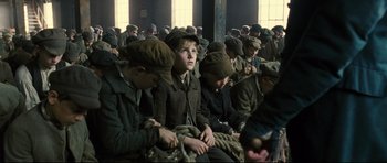 Movie still from “Oliver Twist” (2005), directed by Roman Polanski – A group of young men sitting next to each other in a room; Medium shot, High angle