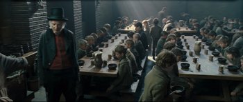 Movie still from “Oliver Twist” (2005), directed by Roman Polanski – A group of children sitting at a long wooden table; Wide shot, High angle
