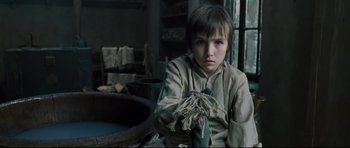 Movie still from “Oliver Twist” (2005), directed by Roman Polanski – A young boy sitting in front of a window; Close Up shot, High angle