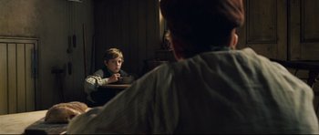 Movie still from “Oliver Twist” (2005), directed by Roman Polanski – A man sitting at a table with a child; Medium shot, Over the shoulder angle