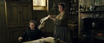 Movie still from “Oliver Twist” (2005), directed by Roman Polanski – Two women in a room with a table and a window in the background; Medium shot, Low angle