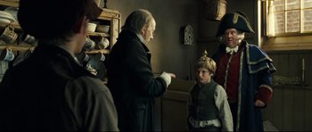 Movie still from “Oliver Twist” (2005), directed by Roman Polanski – An older man and a young boy in a room; Medium shot, Over the shoulder angle