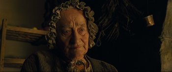 Movie still from “Oliver Twist” (2005), directed by Roman Polanski – An old woman wearing a ruffle hat looking at the camera; Close Up shot, Over the shoulder angle