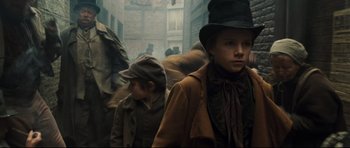 Movie still from “Oliver Twist” (2005), directed by Roman Polanski – A group of young people walking down a street; Medium shot, Low angle
