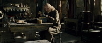 Movie still from “Oliver Twist” (2005), directed by Roman Polanski – A man sitting at a table with a cup of coffee; Medium shot, Over the shoulder angle