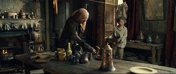 Movie still from “Oliver Twist” (2005), directed by Roman Polanski – A man is pouring tea into a cup; Medium shot, Over the shoulder angle
