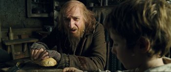 Movie still from “Oliver Twist” (2005), directed by Roman Polanski – An old man with a long beard sitting at a table with a young boy; Close Up shot, Over the shoulder angle