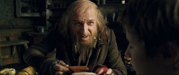 Movie still from “Oliver Twist” (2005), directed by Roman Polanski – An old man with a long beard is holding an apple; Close Up shot, Over the shoulder angle