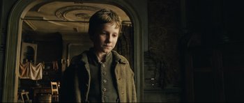 Movie still from “Oliver Twist” (2005), directed by Roman Polanski – A young boy standing in front of an arched doorway; Close Up shot, Low angle