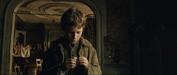 Movie still from “Oliver Twist” (2005), directed by Roman Polanski – A young boy is holding a coin in his hands; Close Up shot, Over the shoulder angle