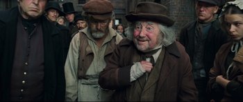 Movie still from “Oliver Twist” (2005), directed by Roman Polanski – A man in a brown hat and a man in a brown suit and tie; Medium shot, Over the shoulder angle
