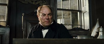Movie still from “Oliver Twist” (2005), directed by Roman Polanski – An older man sitting in a chair with a beard; Close Up shot, Low angle