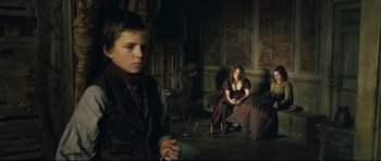 Movie still from “Oliver Twist” (2005), directed by Roman Polanski – A young man and a young woman sitting in a room; Medium shot, Low angle