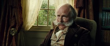 Movie still from “Oliver Twist” (2005), directed by Roman Polanski – An old man with a beard and mustache wearing a suit; Close Up shot, Over the shoulder angle