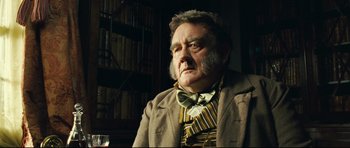 Movie still from “Oliver Twist” (2005), directed by Roman Polanski – An old man with a beard and mustache wearing a jacket and tie; Close Up shot, Low angle
