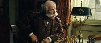 Movie still from “Oliver Twist” (2005), directed by Roman Polanski – An old man sitting in front of a chessboard; Close Up shot, Over the shoulder angle