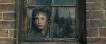 Movie still from “Oliver Twist” (2005), directed by Roman Polanski – A young boy looking out of a broken window; Close Up shot, Low angle