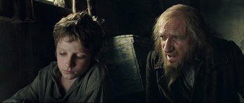 Movie still from “Oliver Twist” (2005), directed by Roman Polanski – A man and a boy are sitting next to each other; Close Up shot, Over the shoulder angle