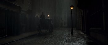 Movie still from “Oliver Twist” (2005), directed by Roman Polanski – A man riding a horse drawn carriage down a street; Extreme Wide shot, High angle