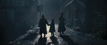 Movie still from “Oliver Twist” (2005), directed by Roman Polanski – A man , woman , and a child walking down a street; Wide shot, Low angle