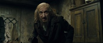 Movie still from “Oliver Twist” (2005), directed by Roman Polanski – An old man with a long beard is looking at the camera; Medium shot, Low angle